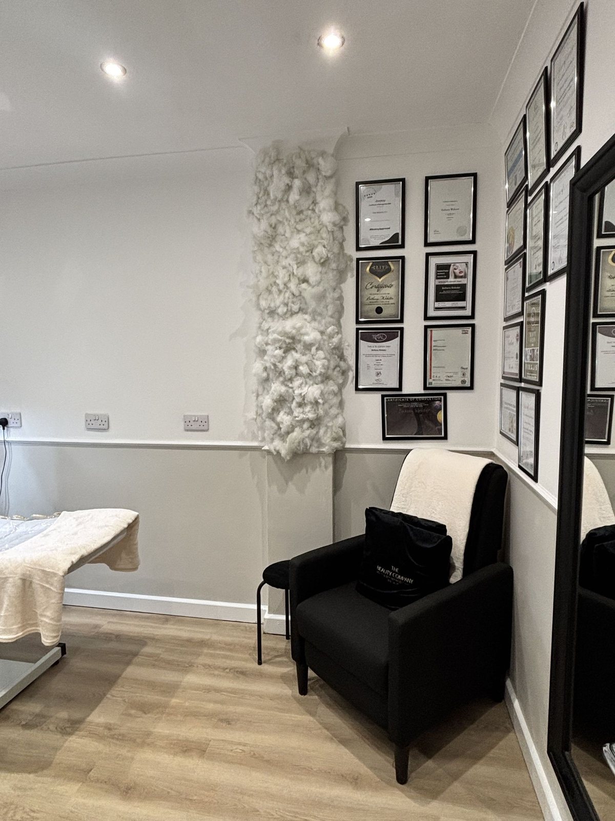 An armchair in the corner of the treatment room beneath framed certificates