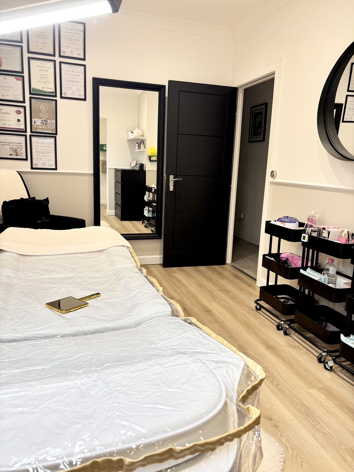 The treatment bed with framed certificates and a full length mirror